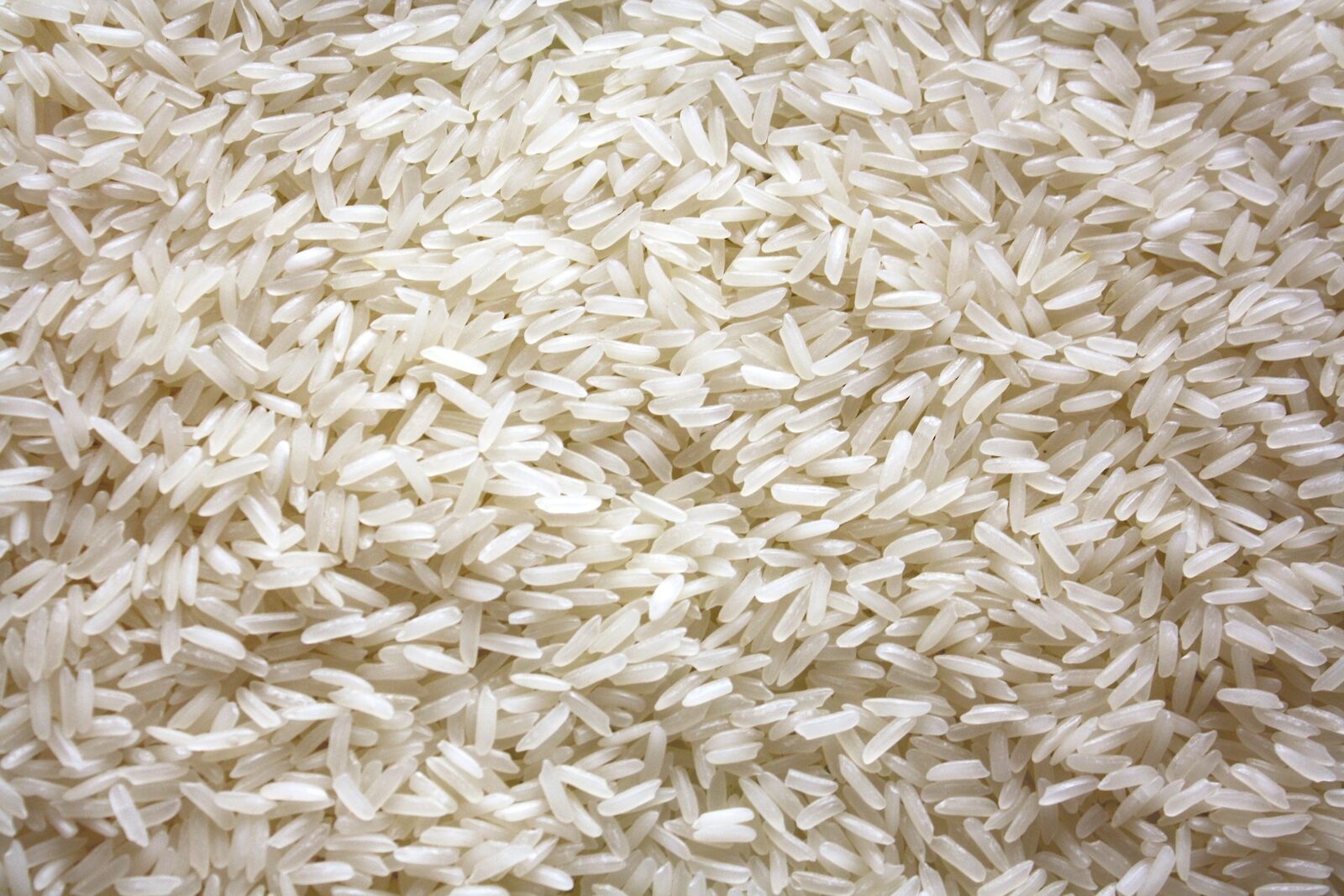 A pile of uncooked white rice photographed from directly overhead — individual grains visible, even natural light.